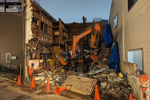 Démolition d'une maison ancienne, gravats et pelleteuse sur la parcelle
